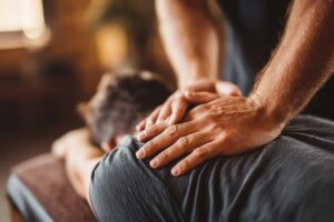 A person sitting in a calm, softly lit room receiving a gentle chiropractic adjustment.