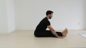 Person performing gentle seated mobility exercises on a chair in a bright home setting.